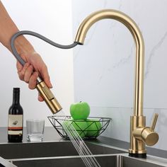 a person is washing an apple in a sink with a faucet and soap dispenser