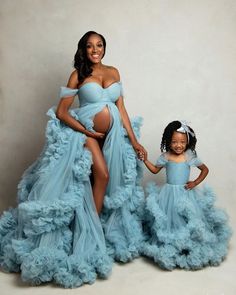 a pregnant woman and her daughter pose for a photo in blue gowns with ruffled skirt