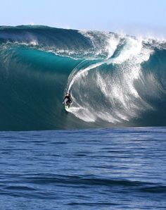 a man riding a wave on top of a surfboard in the middle of the ocean