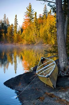 a canoe sitting on top of a rock next to a body of water