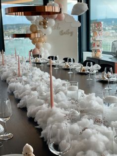 a long table covered in white fluffy clouds with candles and balloons hanging from the ceiling