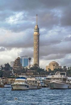 several boats are docked in the water near a tall tower