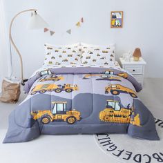 a bed with construction themed comforter and pillows on it in a white room next to a lamp