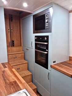 an oven built into the side of a wooden counter top in a kitchen with stairs leading up to it