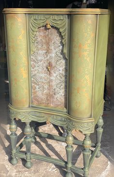 an old fashioned green cabinet with ornate carvings on it's sides and doors,