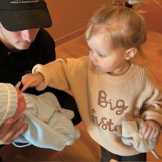 a man is holding a baby in his arms and looking at something on the floor