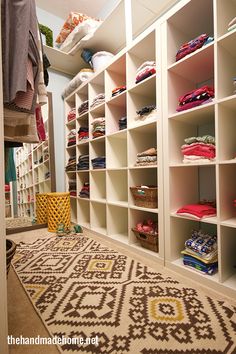 the closet is filled with lots of clothes and baskets on shelving units, including an area rug