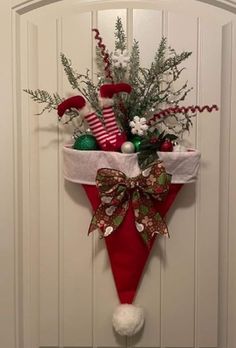 a red and white christmas decoration hanging on a door with stockings, candy canes, holly cones and other holiday decorations