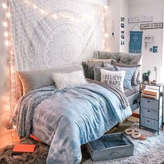 an unmade bed in a bedroom with string lights on the headboard and pillows