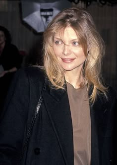 a woman in a black jacket and brown shirt is posing for the camera with her hand on her hip