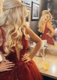 a woman in a red dress looking at herself in the mirror