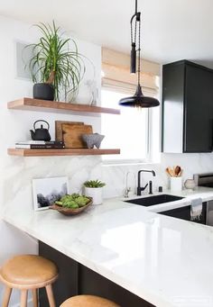 a kitchen with black cabinets and white counter tops, two stools in front of the sink