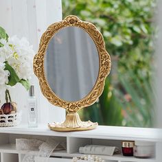 a mirror sitting on top of a white shelf next to a vase filled with flowers