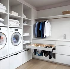 a washer and dryer sitting in a room next to a shelf with clothes on it