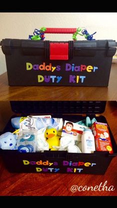 a black box filled with diapers and toys on top of a wooden table next to a wall