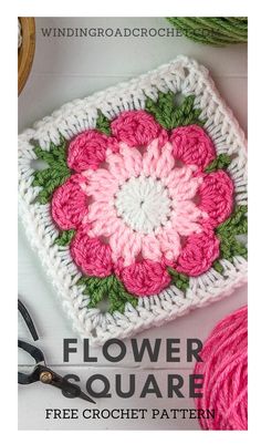 a crocheted square with pink flowers on it and green leaves in the center