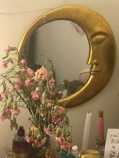 a vase with flowers in it sitting on a table next to a mirror and bottles