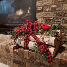 a red bird sitting on top of a log next to a fire place with christmas decorations