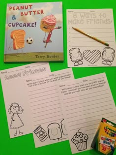 some food and writing materials on a green table with a cupcake, peanut butter and other items