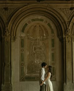 a bride and groom kissing in an old building