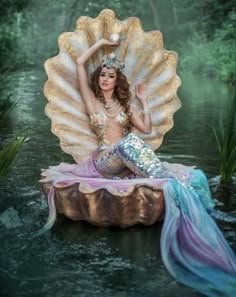 a beautiful woman in a mermaid costume sitting on a shell with her hands behind her head