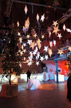 a large room filled with lots of lights and stars hanging from the ceiling over tables