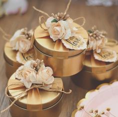 four gold boxes with flowers on them are sitting on a table next to each other