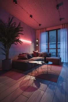 a living room filled with furniture and a large window covered in pink light next to a potted plant