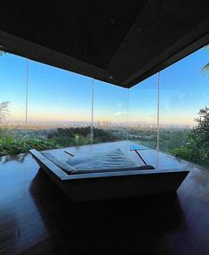 a large bath tub sitting on top of a wooden floor next to tall glass windows