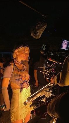 a woman standing in front of a camera on top of a tripod at night