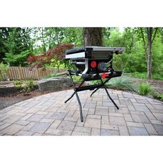 a black and red portable table saw sits on a brick patio in the middle of a garden