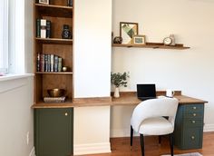 a desk with a laptop on top of it next to a book shelf filled with books