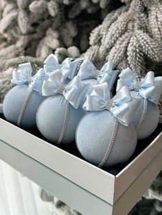 four baby blue shoes with bows are in a box on the shelf next to a christmas tree