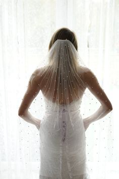 the back of a bride's veil as she stands in front of a window