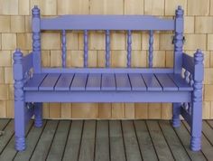 a purple bench sitting on top of a wooden floor next to a brick wall with wood slats