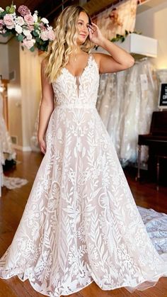 a woman in a white wedding dress standing on a wooden floor with her hands behind her head