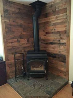 a wood burning stove in a room with wooden walls and floor boards on the wall