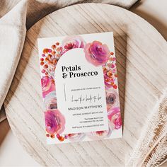 the wedding program is displayed on a wooden plate with white linens and pink flowers