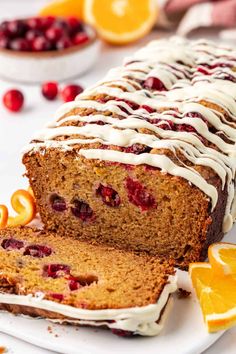 a loaf of cranberry orange bread with icing on a white platter