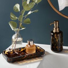 a vase and soap dispenser sitting on a counter next to a mirror