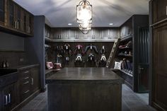 a walk in closet filled with lots of coats and shoes on shelves next to a sink