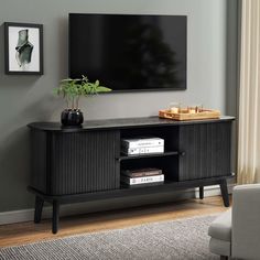 a living room with a large flat screen tv mounted on the wall above a wooden entertainment center