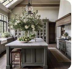 a large kitchen with an island in the middle and lots of greenery on it