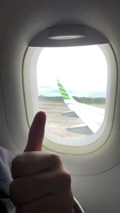 a person giving the thumbs up in front of an airplane window