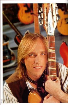 a man holding an electric guitar in front of his face and smiling at the camera