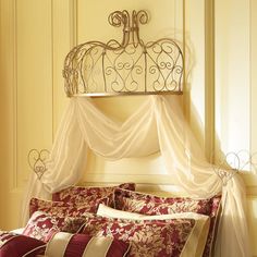 a bed with a canopy over it and pillows on the bottom side, in a room with yellow walls