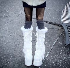 a woman in white boots standing next to a bench