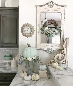 the kitchen counter is decorated with white flowers and pumpkins on it, along with an ornate mirror