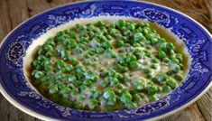 a bowl filled with peas on top of a wooden table