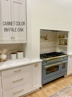 a kitchen with white cabinets and an oven in the center is decorated with gold trim